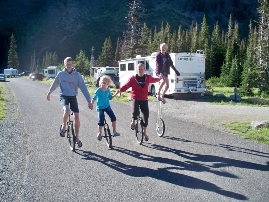 Photo from the 2012 Christmas letter: children riding bicycles and a unicycle on a campground road